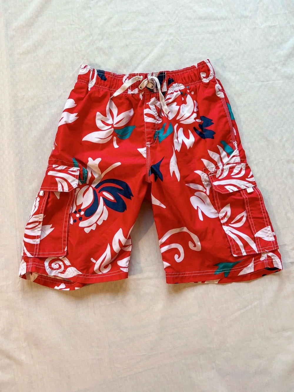 red swim trunks with white and blue tropical print